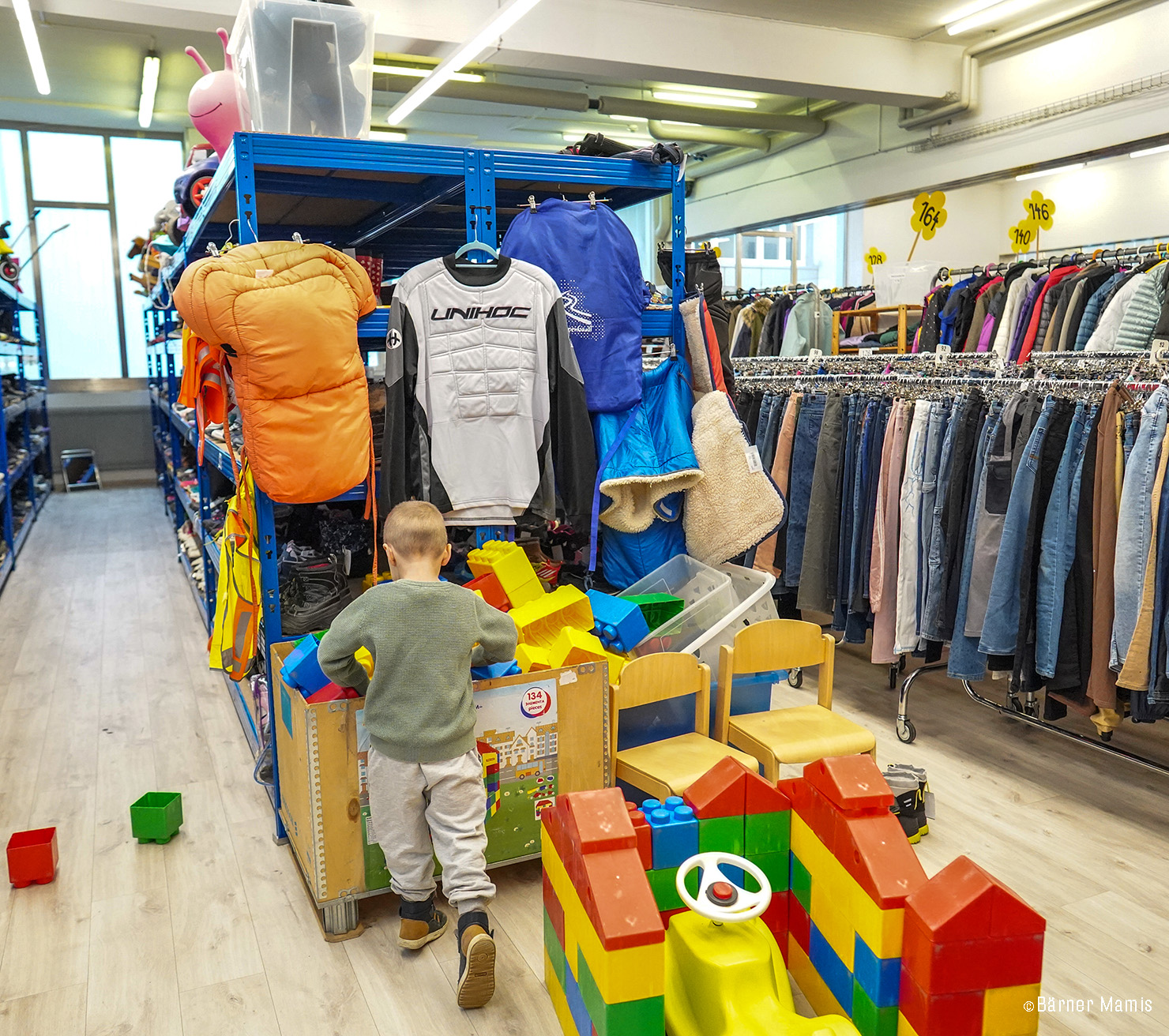 Ein Junge spielt mit grossen Bauklötzen in einer Kinderkleiderbörse.